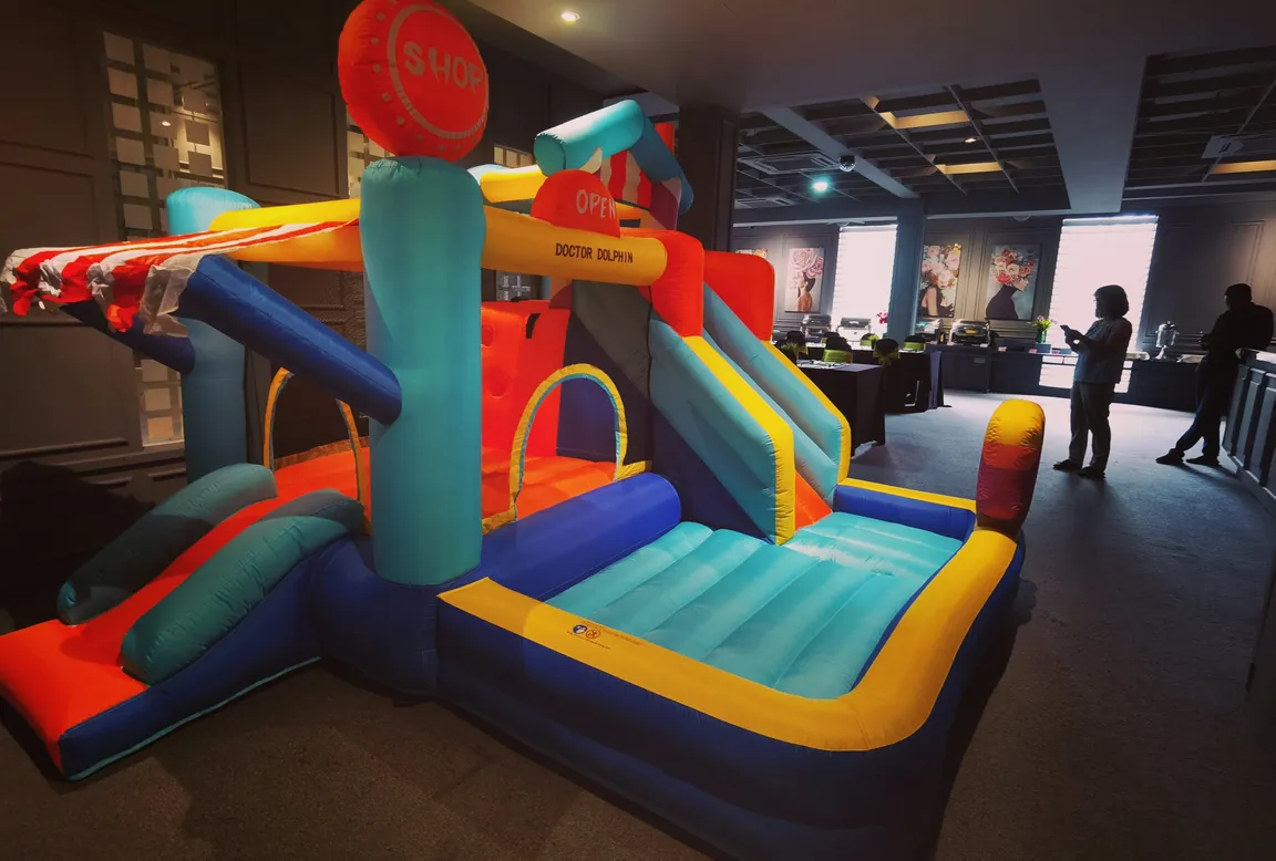 Blue and orange bouncy castle with a slide, set up indoors for an event