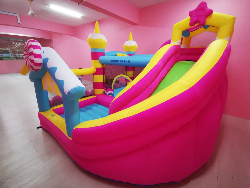 Pink and yellow bouncy castle with a slide