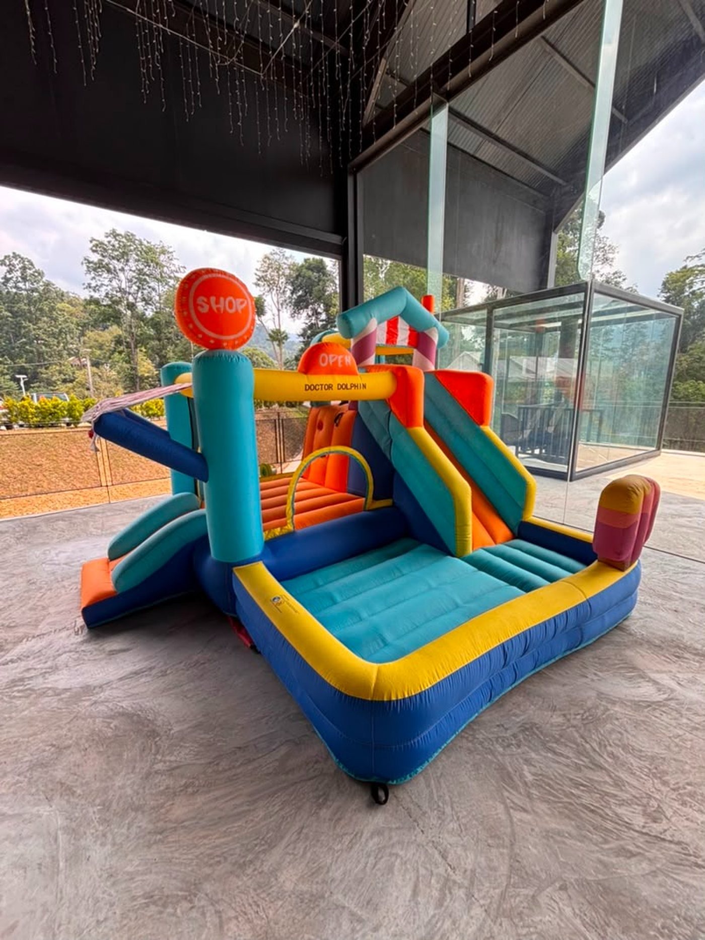 Bouncy castle with slide and ball pool set up on a covered outdoor terrace with hills in the background